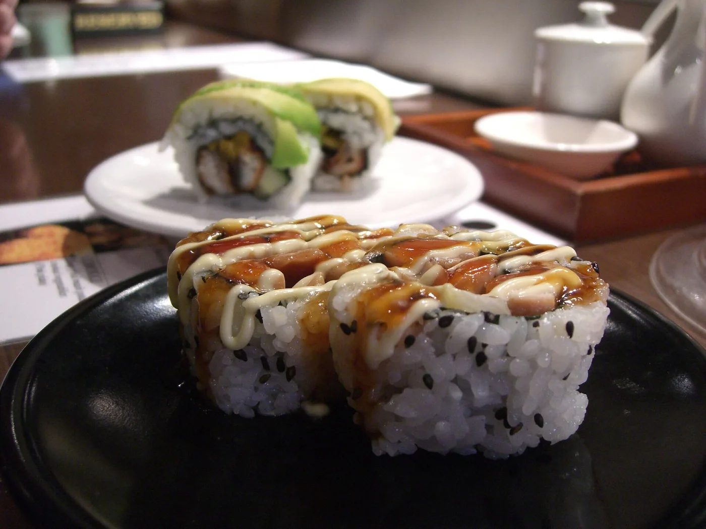 Sushirollen mit Teriyakisauce und Sesam auf schwarzem Teller