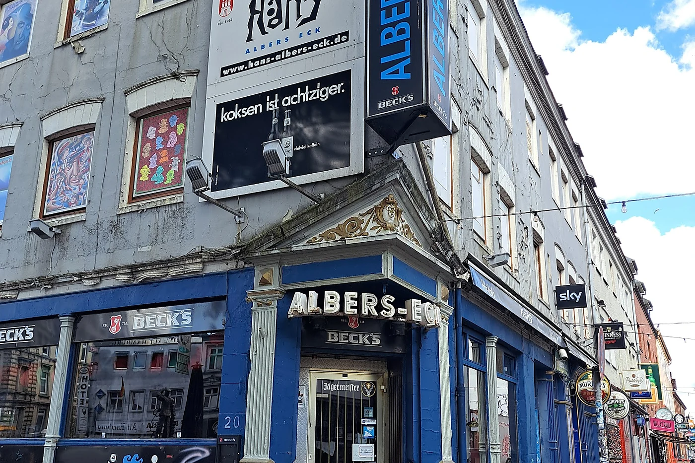 Blau gestrichene Eckkneipe Hans-Albers-Eck bei Tageslicht mit Leuchtschrift ALBERS-ECK und Beck’s-Schildern