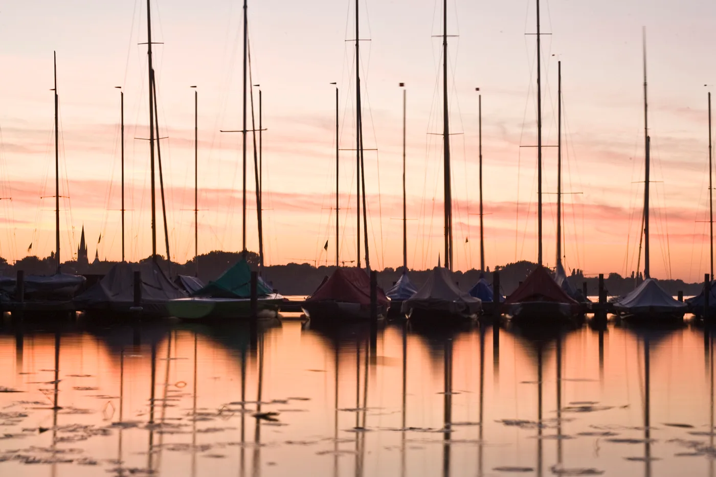 Segelboote auf der Außenalster im Sonnenuntergang mit Spiegelungen im Wasser