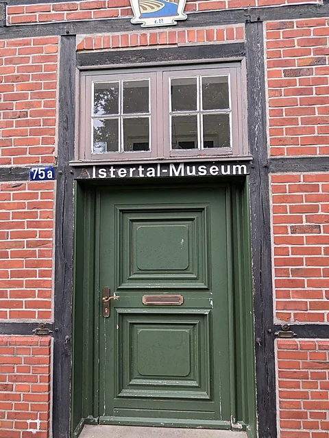 Grüne Eingangstür des Alstertal-Museums im Fachwerk des Torhauses mit dem Schild „Alstertal-Museum“ und der Hausnummer 75a