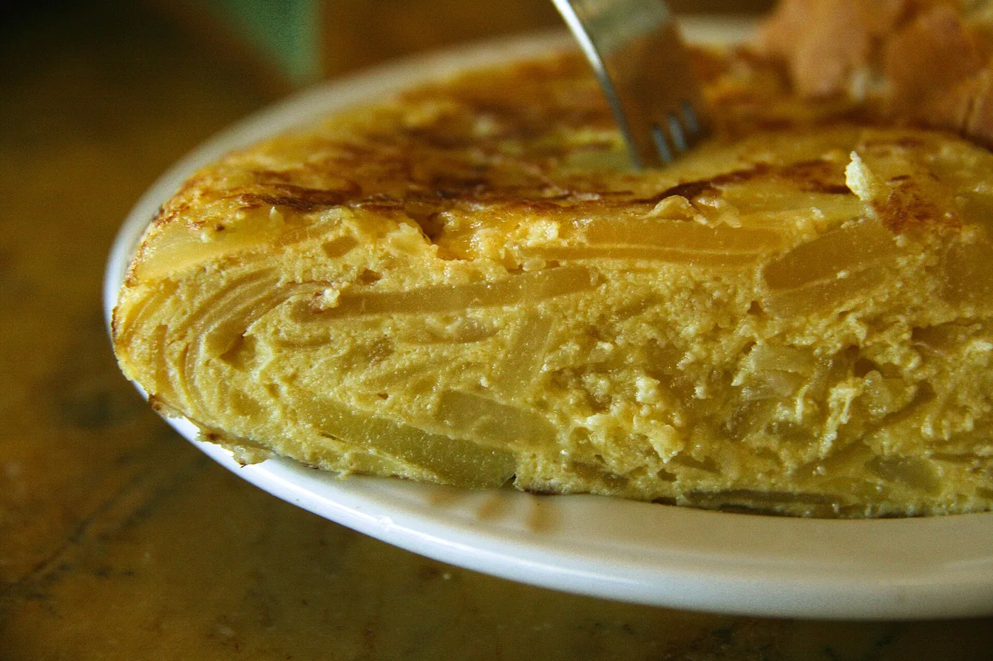 Angeschnittene spanische Kartoffeltortilla auf einem weißen Teller