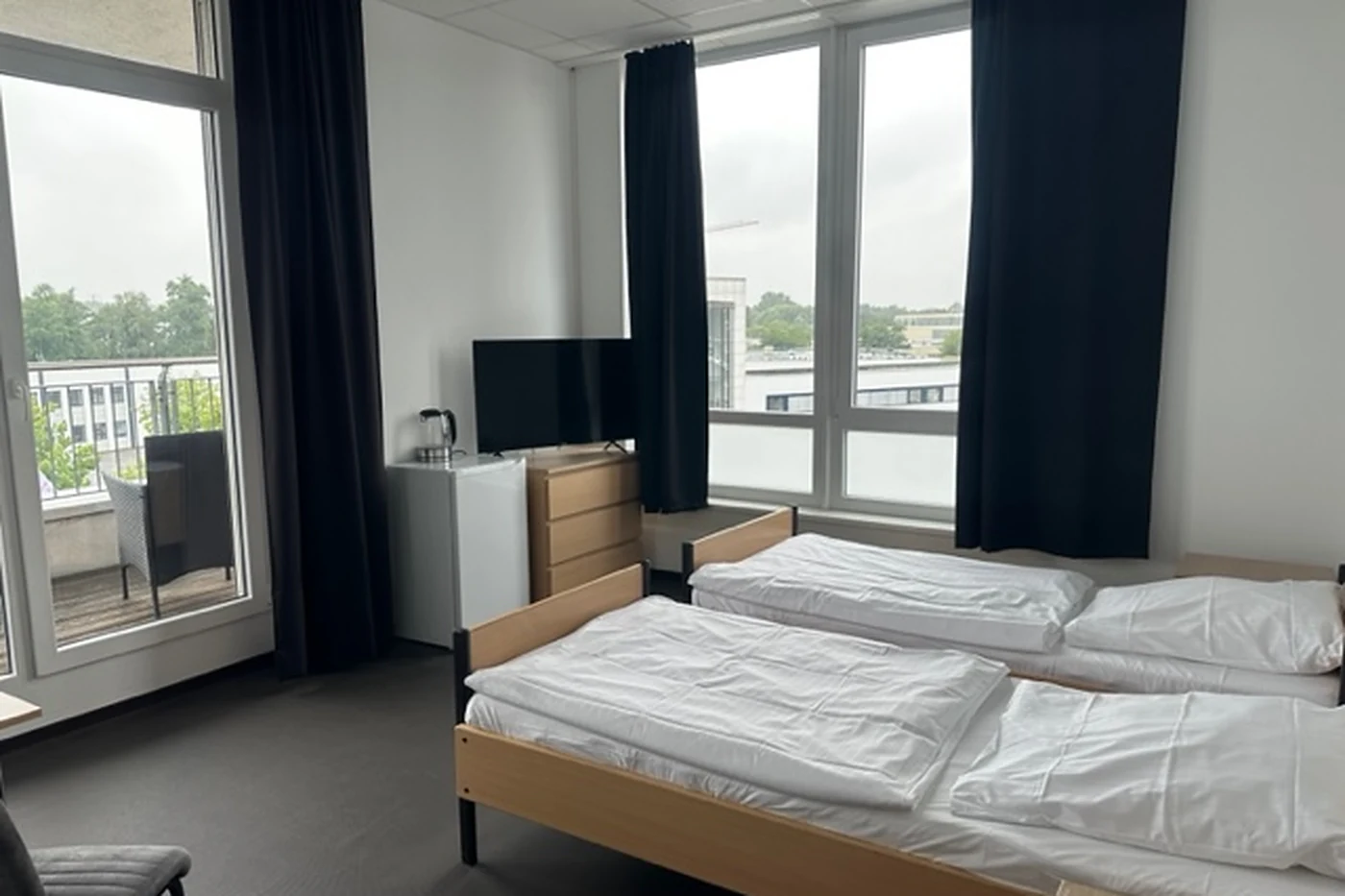 Zimmer mit Doppelbett, Schrank und bodentiefem Fenster