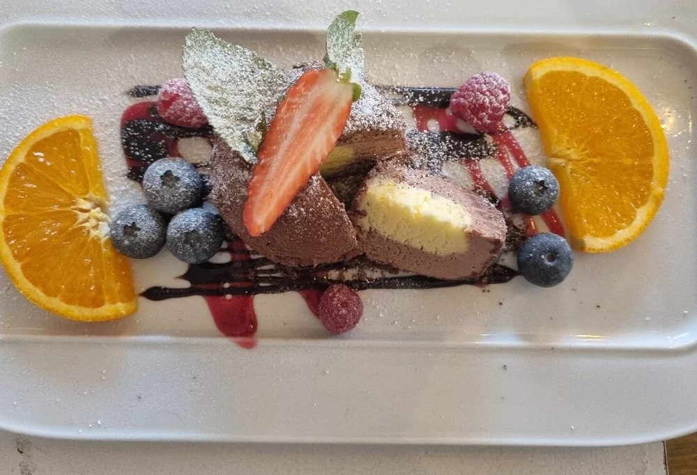 Dessertteller mit Schokoladenmousse, Vanilleeis, Erdbeere, Blaubeeren und Orangenscheiben