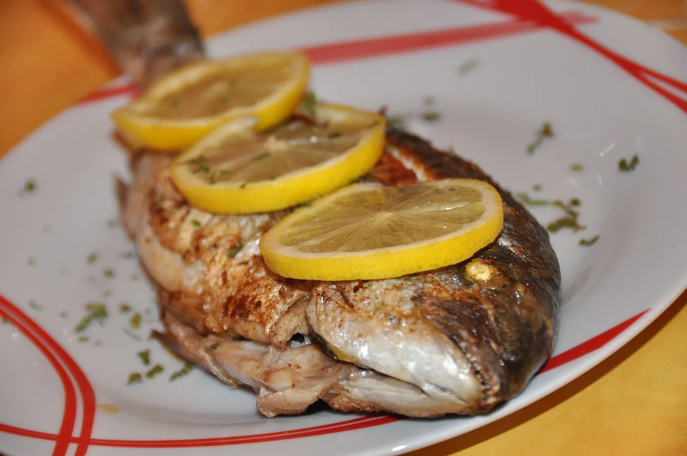 Gegrillte Dorade mit Zitronenscheiben auf einem Teller