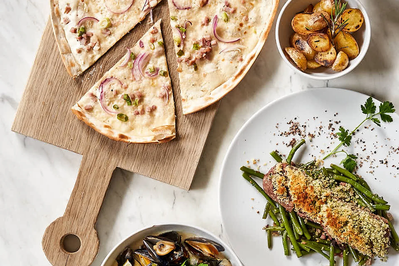 Flammkuchen, Bowl und Pommes auf einem Holzbrett