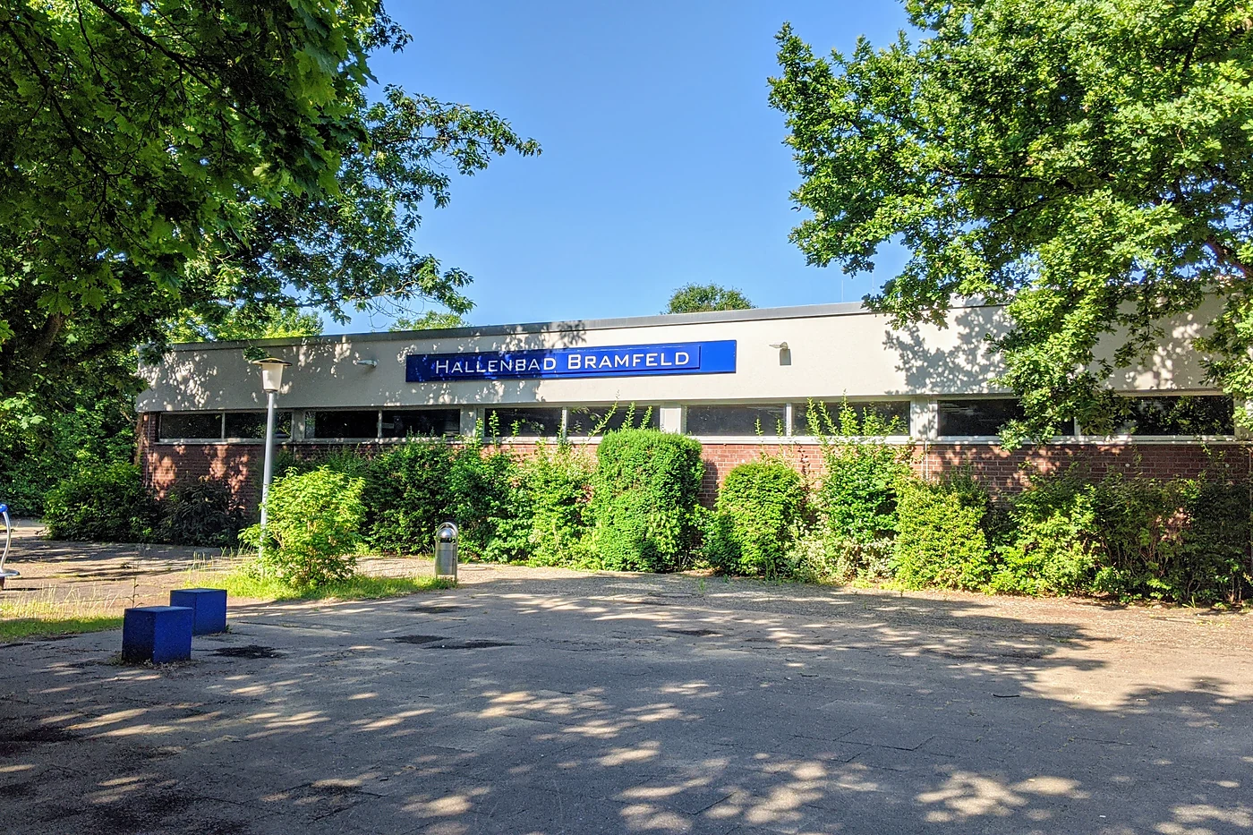 Flachbau des Hallenbads Bramfeld mit blauem Schriftzug an der Fassade