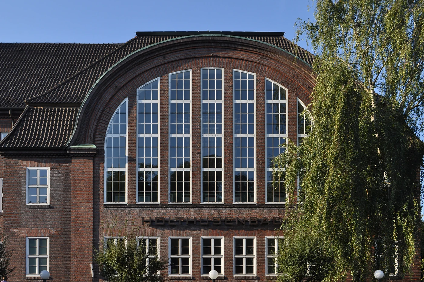 Detail der Rundbogenfassade des Bades mit Sprossenfenstern und Ziegelmauerwerk