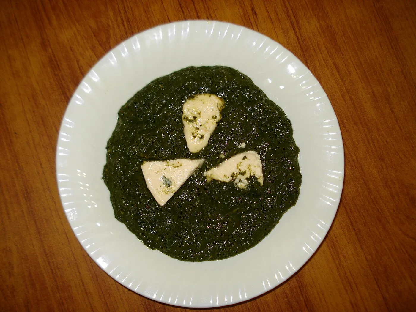 Palak Paneer, Spinat mit Käsestücken auf weißem Teller