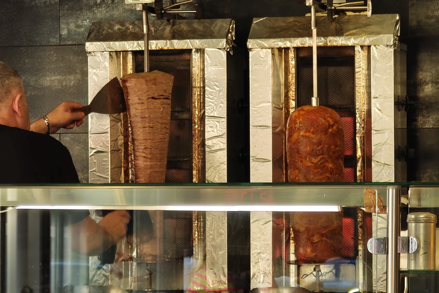 Dönerspieß am senkrechten Grill hinter der Theke