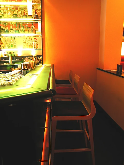 Tresen der Bar Monopol mit beleuchtetem Flaschenregal und Barhockern