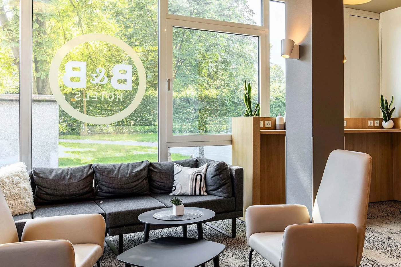 Lounge mit Sesseln und Sofa vor bodentiefen Fenstern