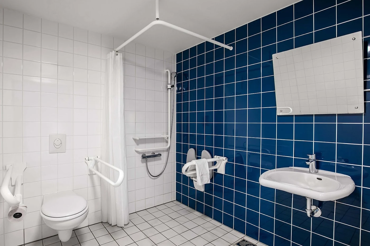 Barrierefreies Bad mit blauen Fliesen und Haltegriffen