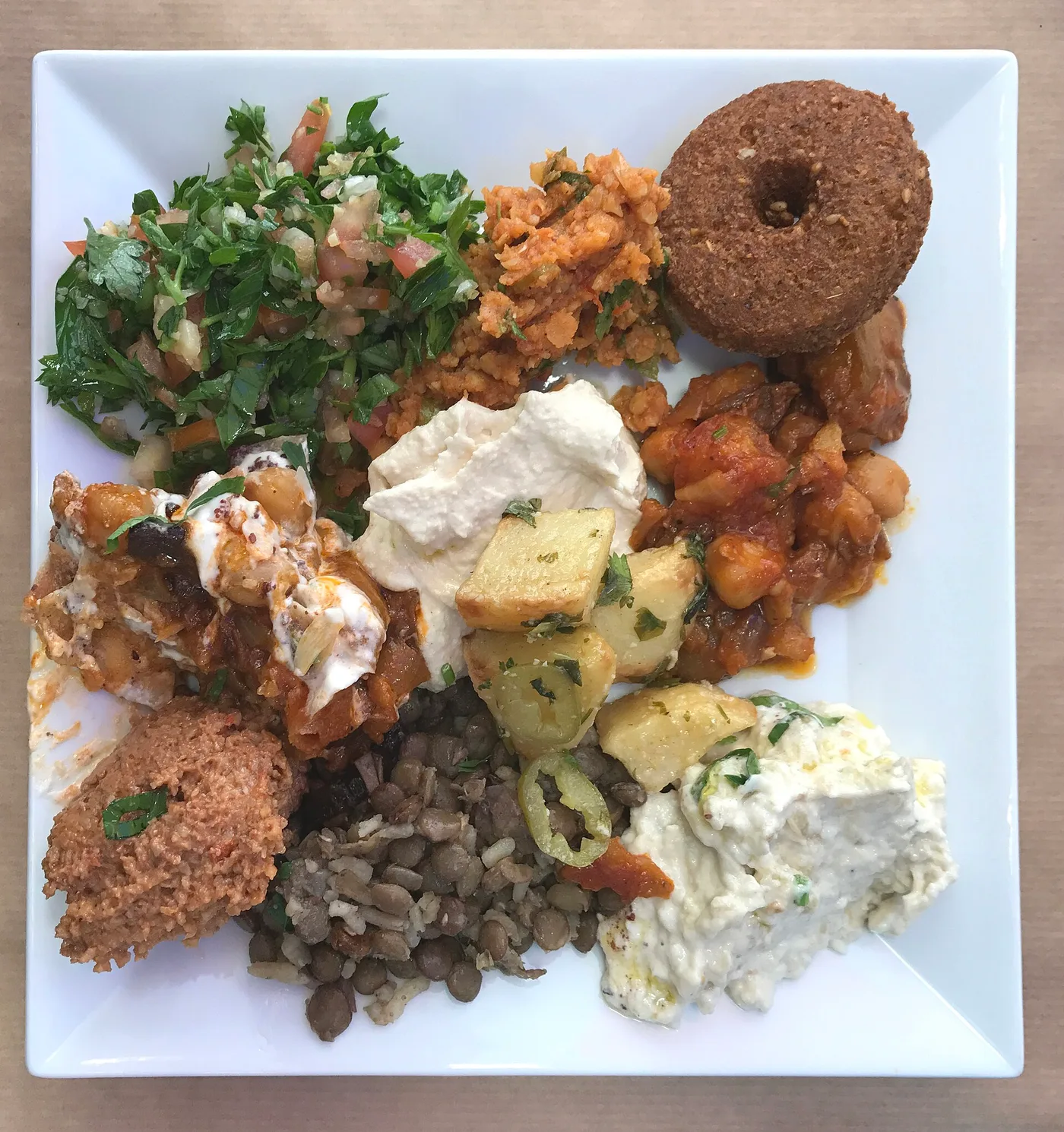 Quadratischer Teller mit Tabbouleh, Kibbeh, Hummus, Linsen und Auberginen