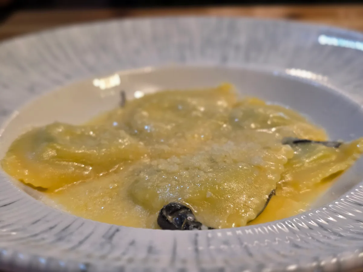 Ravioli in Salbeibutter mit geriebenem Käse auf einem weißen Teller
