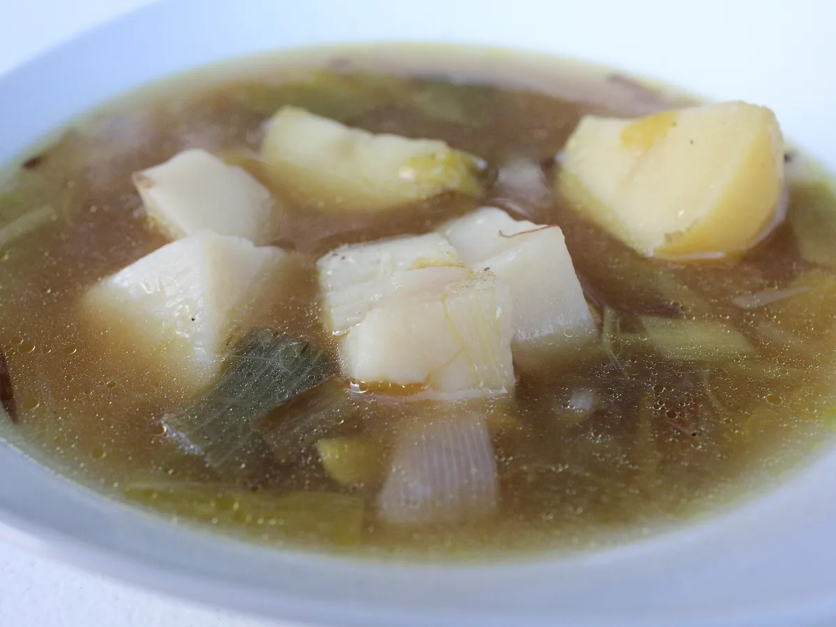 Klare Lauchsuppe mit Kartoffelstücken in einem weißen Teller