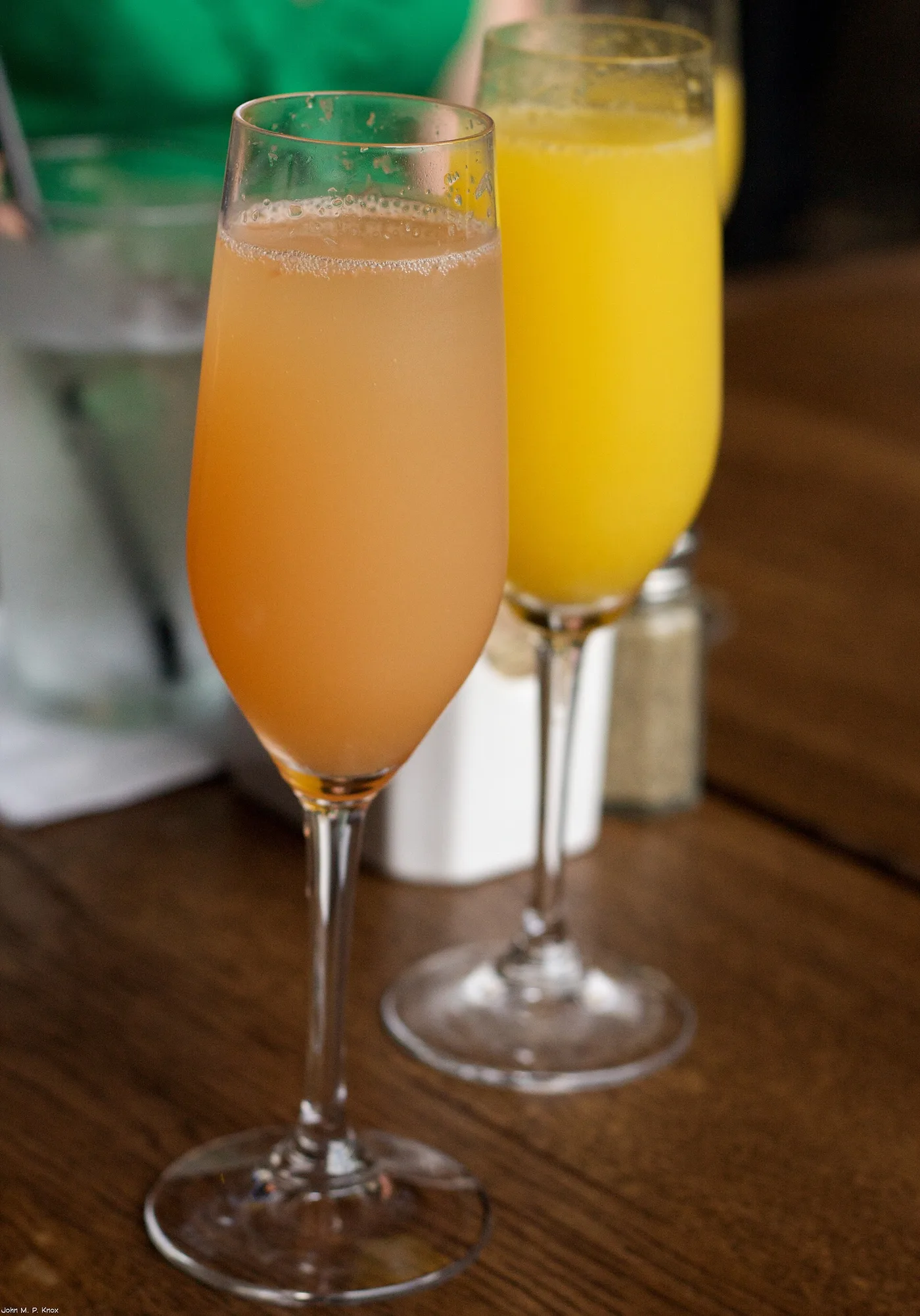 Zwei Sektgläser mit Mimosa aus Grapefruit- und Orangensaft auf einem Holztisch