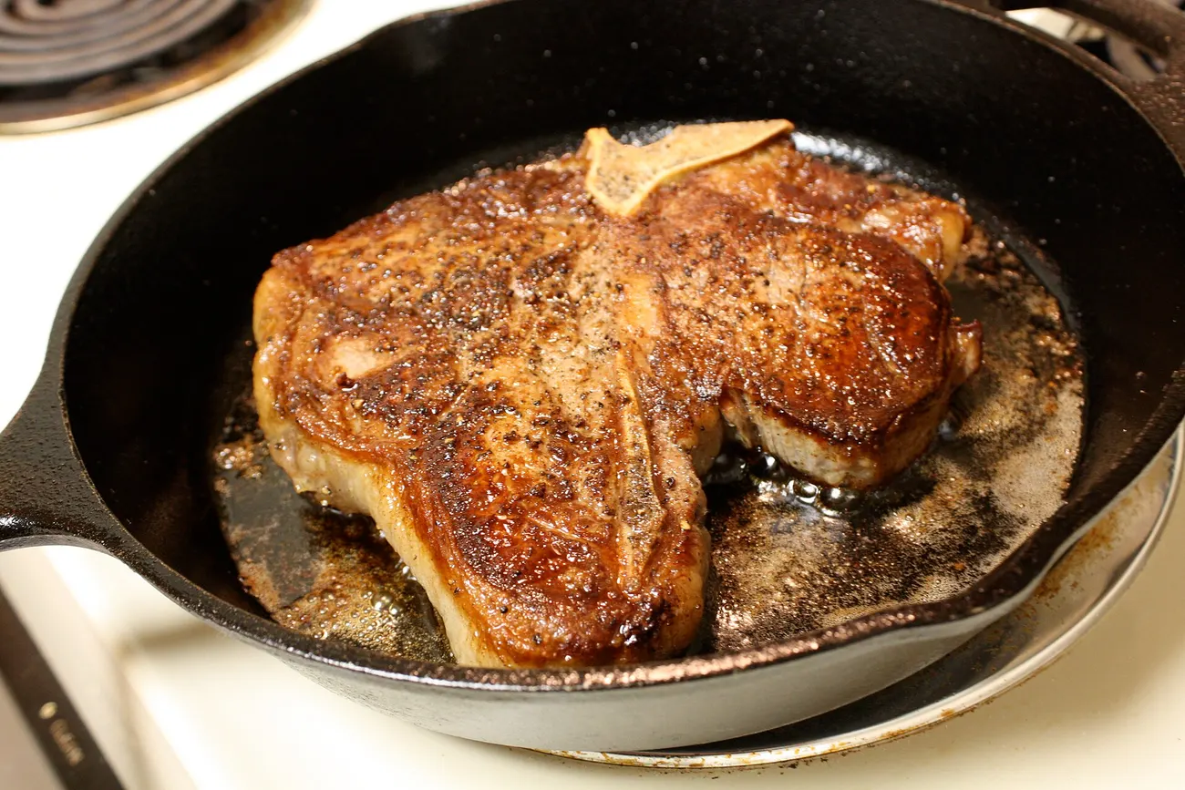 Steak brät in einer gusseisernen Pfanne auf dem Herd