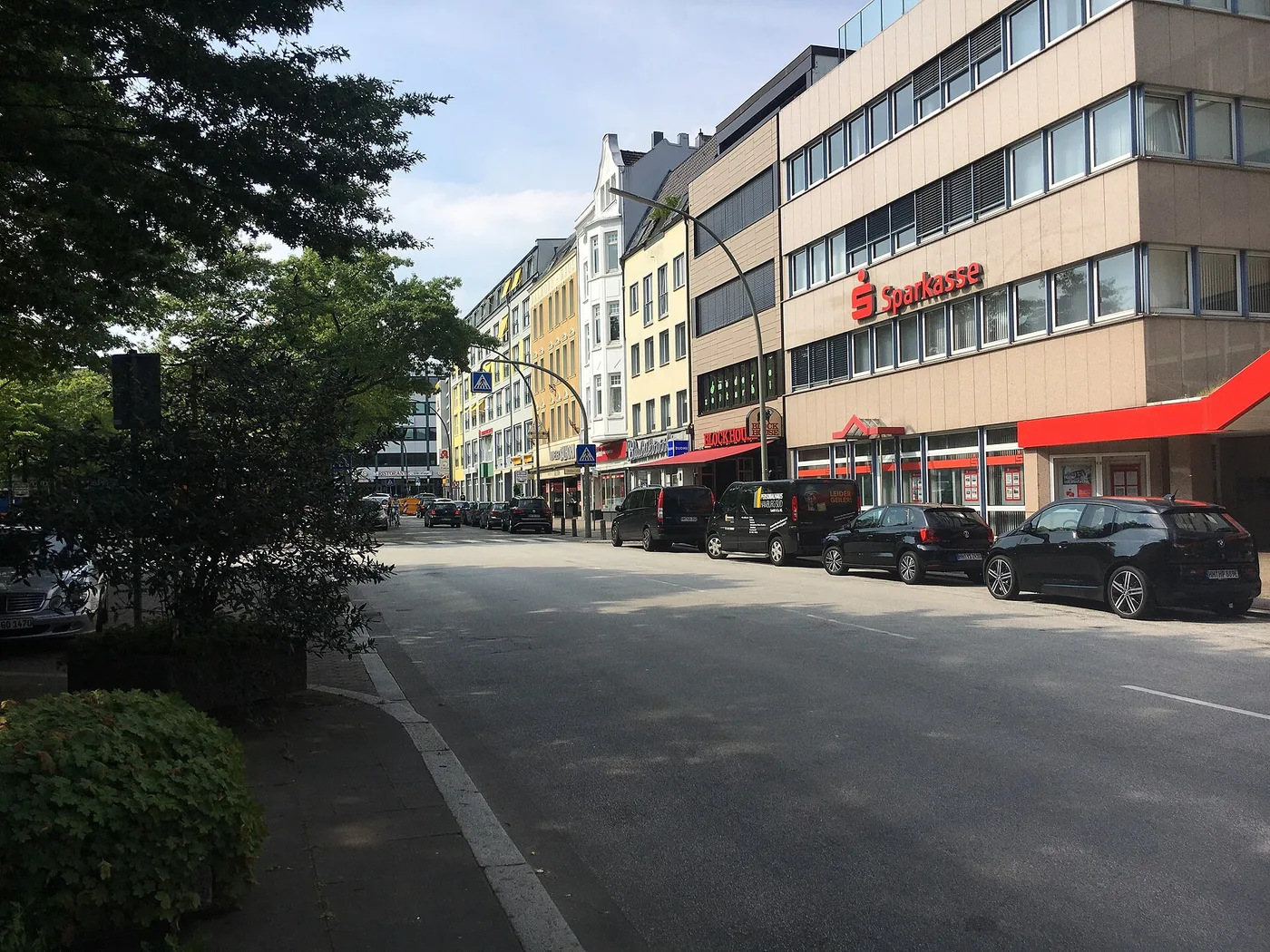 Straßenzug am Sand in Harburg mit Geschäften und geparkten Autos