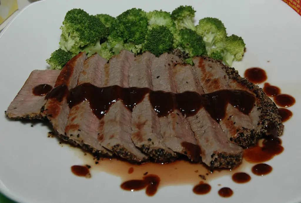Gebratenes Steak mit Kräuterbutter, Kartoffelpüree und Salat auf schwarzem Teller