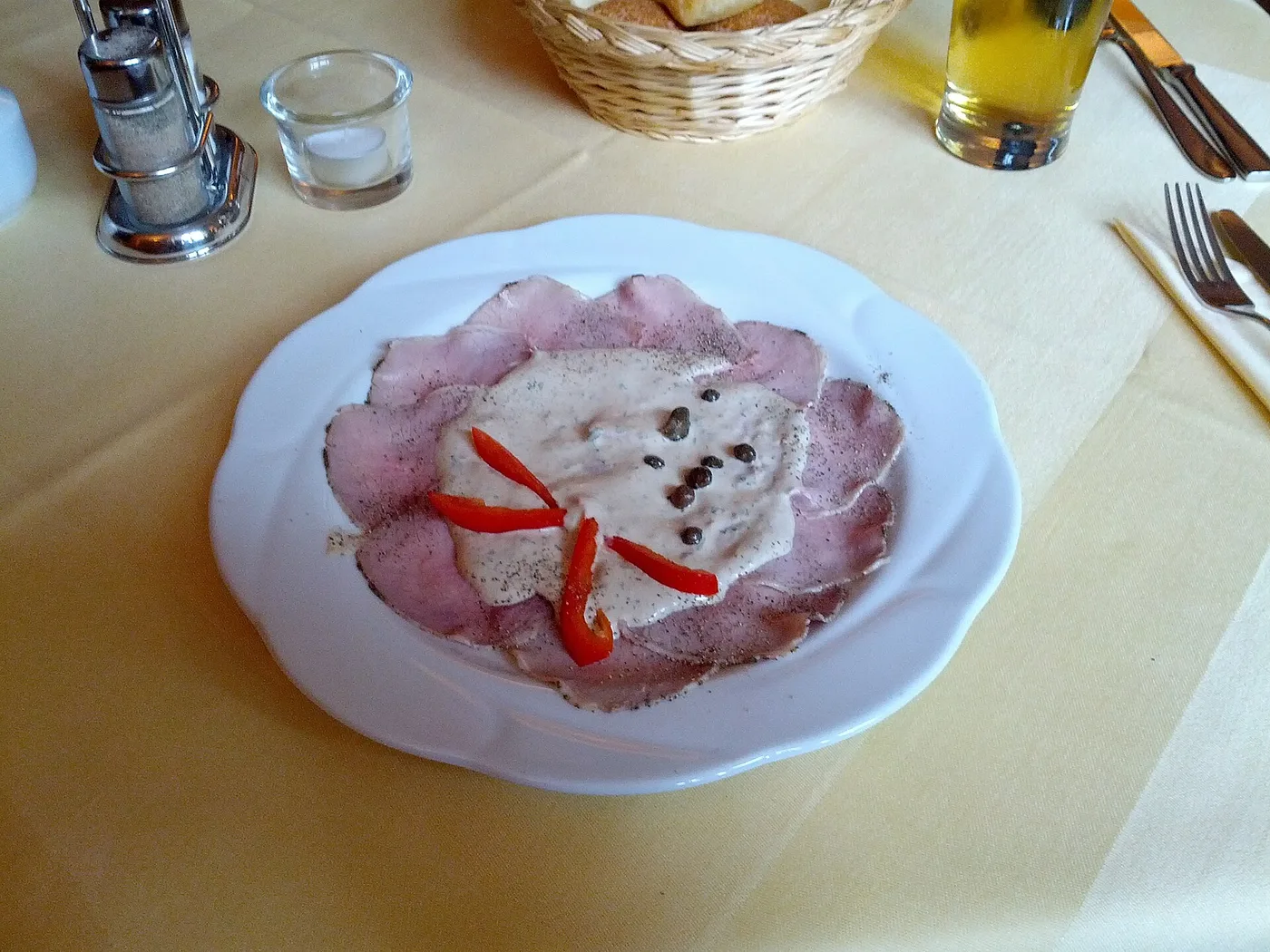 Vitello Tonnato, dünne Kalbfleischscheiben mit Thunfischsauce und Kapern auf gedecktem Tisch
