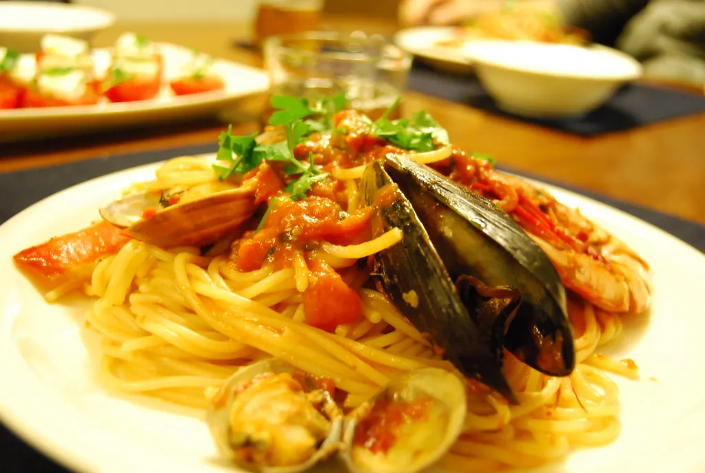 Spaghetti mit Muscheln, Garnelen und Tomatensauce auf weißem Teller