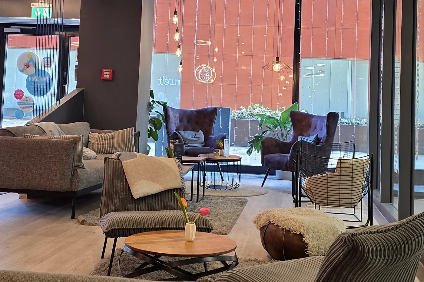Lounge mit Sofas, Sesseln, Couchtisch und Teppich vor einer hohen Fensterfront