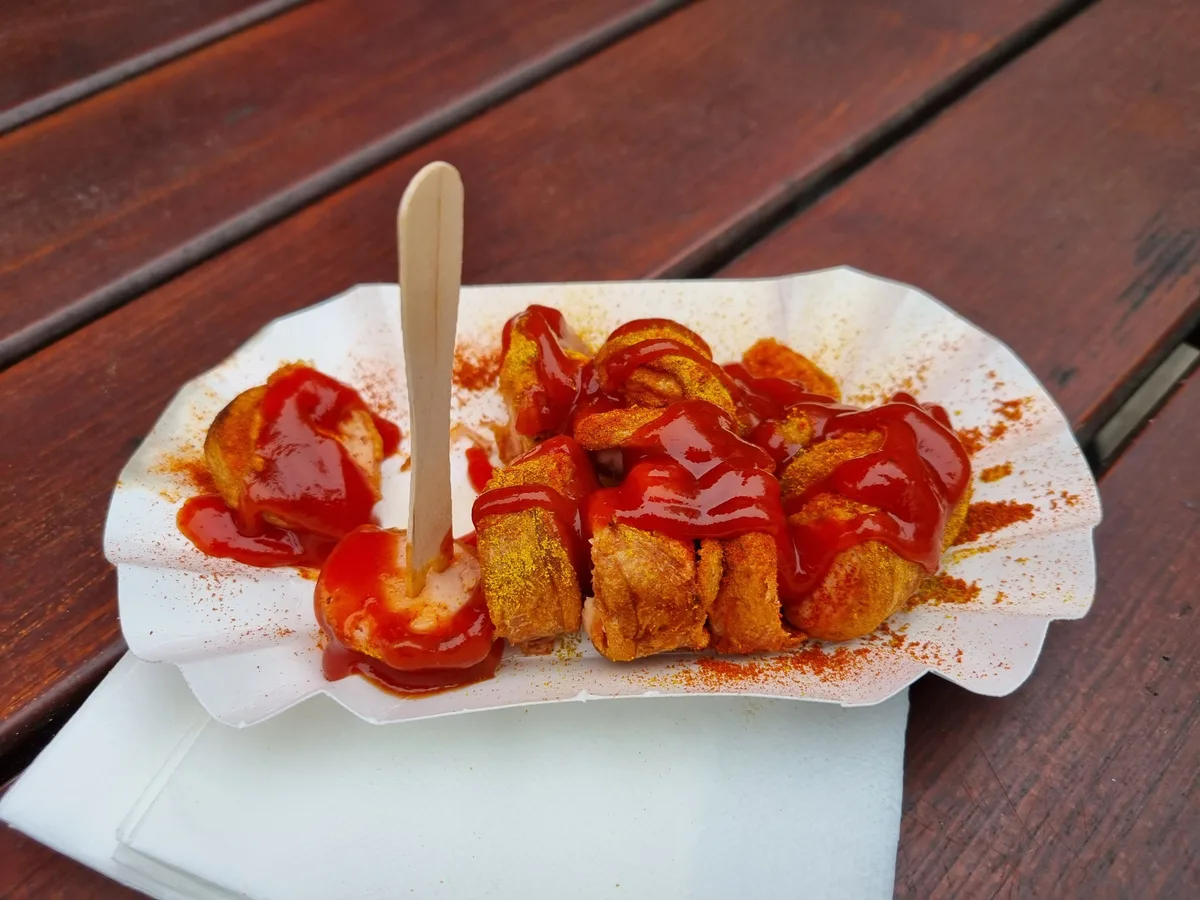 Currywurst in Scheiben mit Sauce und Currypulver in einer Pappschale