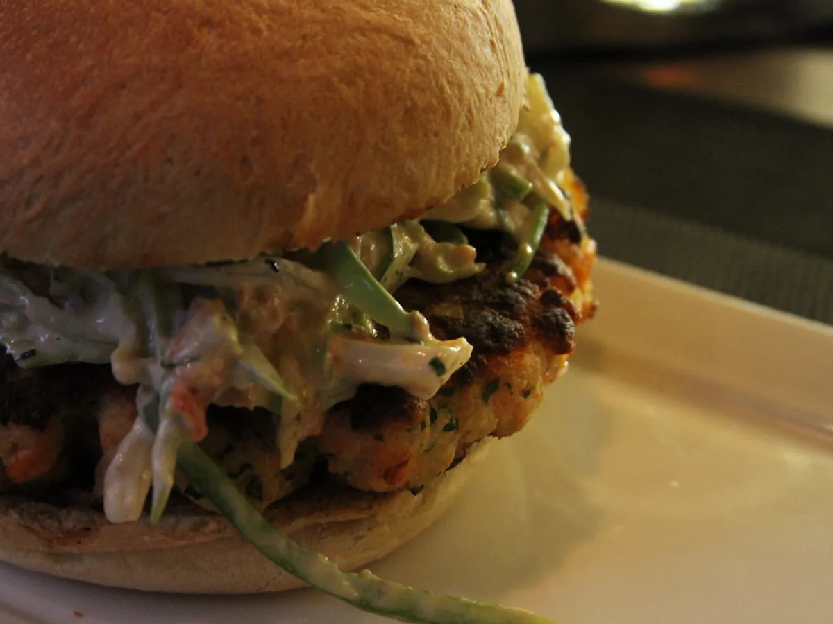 Burger mit gebratenem Lachsfilet und Krautsalat in einem hellen Brötchen
