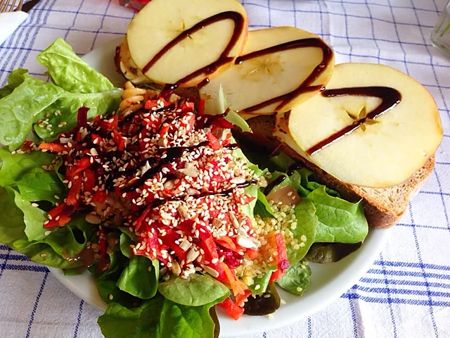 Salat mit Rote Bete, Sesam und Kräutern, dazu Brot mit Apfelscheiben und Balsamico auf einem Teller auf blau-karierter T