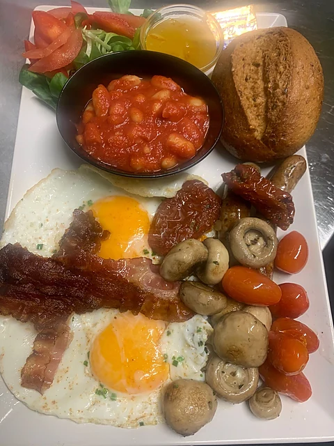 English Breakfast mit Spiegeleiern, Bauernspeck, Bohnen in Tomatensoße, Würstchen, Champignons, Tomaten und Brötchen