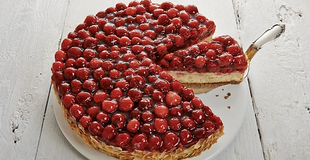 Angeschnittene Himbeertorte mit dicht gesetzten Himbeeren auf Vanillecreme, ein Stück auf dem Tortenheber