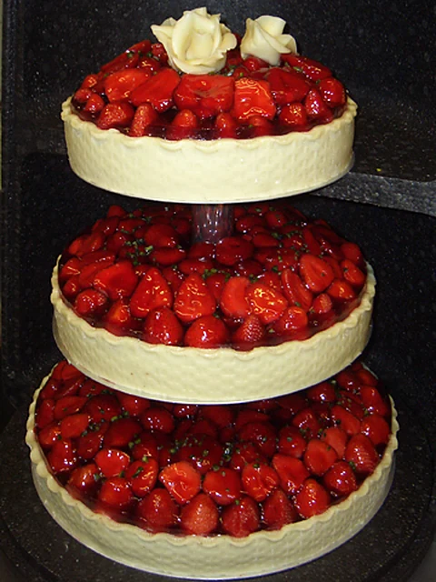 Dreistöckige Erdbeertorte mit glasierten Erdbeeren und Marzipanrosen auf einer Etagere