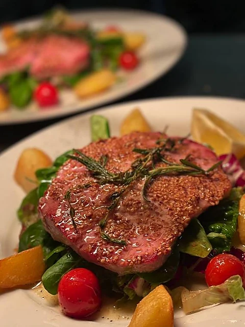 Rosa gebratenes Straußenfilet mit Rosmarin auf Salat mit Cherrytomaten und Bratkartoffeln