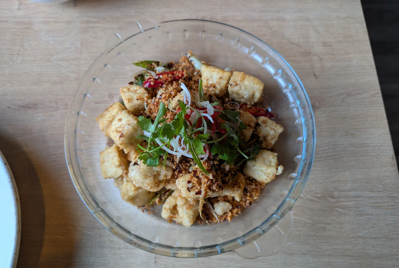 Knusprig frittierte Tofuwürfel mit Chili, Koriander und Frühlingszwiebeln in einer Glasschale