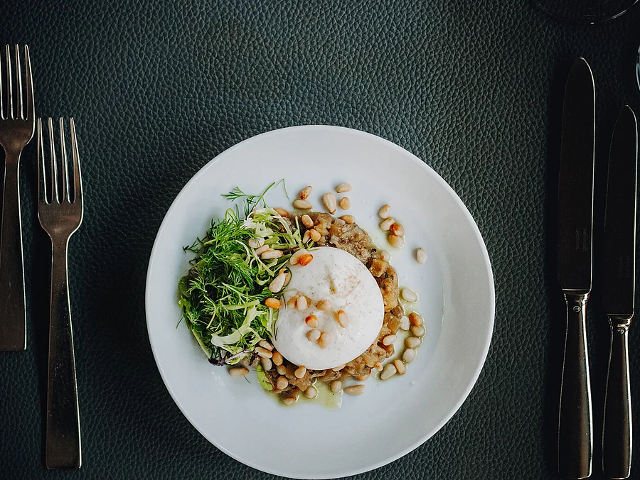 Burrata mit Kichererbsen, Kräutersalat und Olivenöl auf weißem Teller von oben