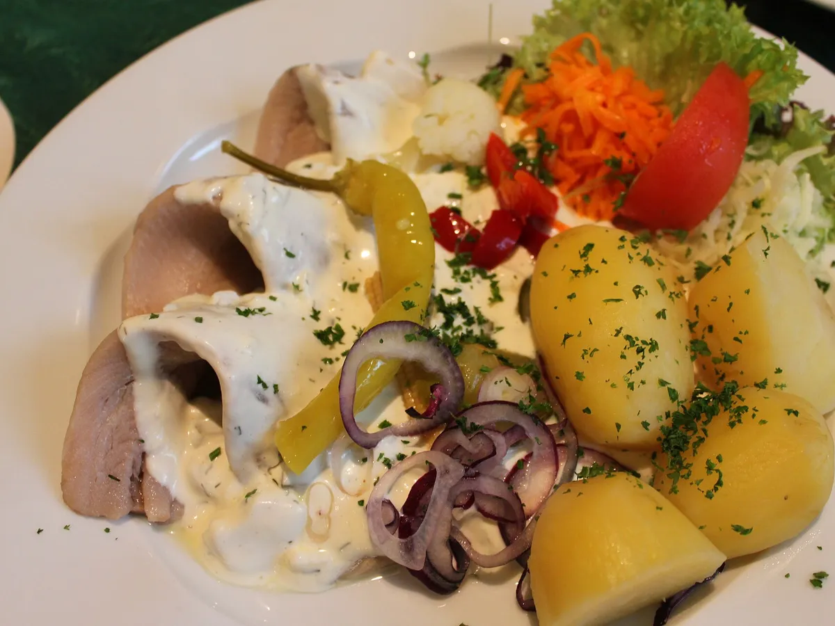 Matjesfilets mit heller Sahnesauce, Salzkartoffeln, roten Zwiebeln und Salat