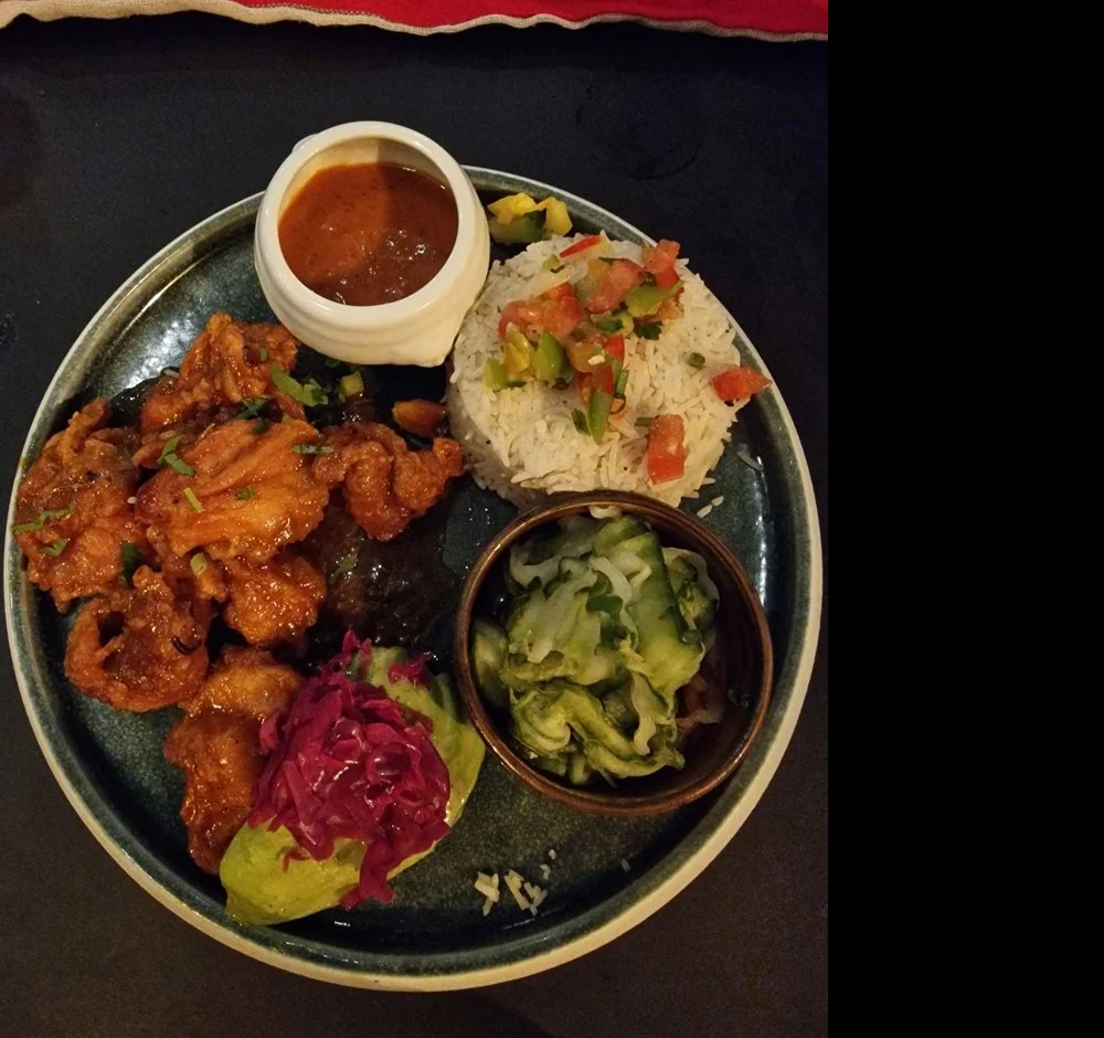 Crispy Chipotle Chicken mit Reis, Pico de Gallo, Salat und Salsa auf dunklem Teller