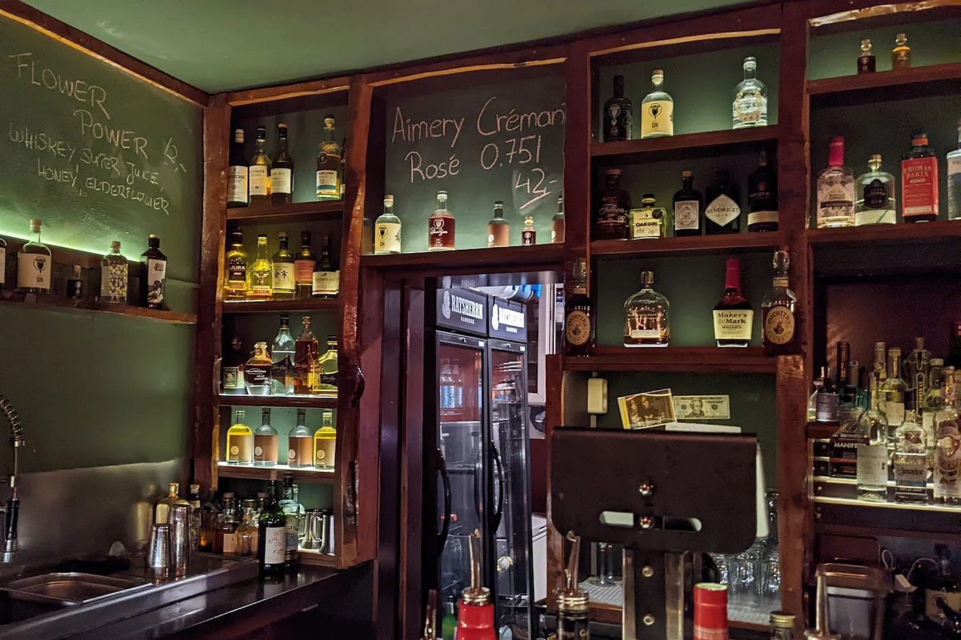 Rückwand der clockers Bar mit grüner Tafelwand, Kreideschrift und Ginflaschen in Regalen