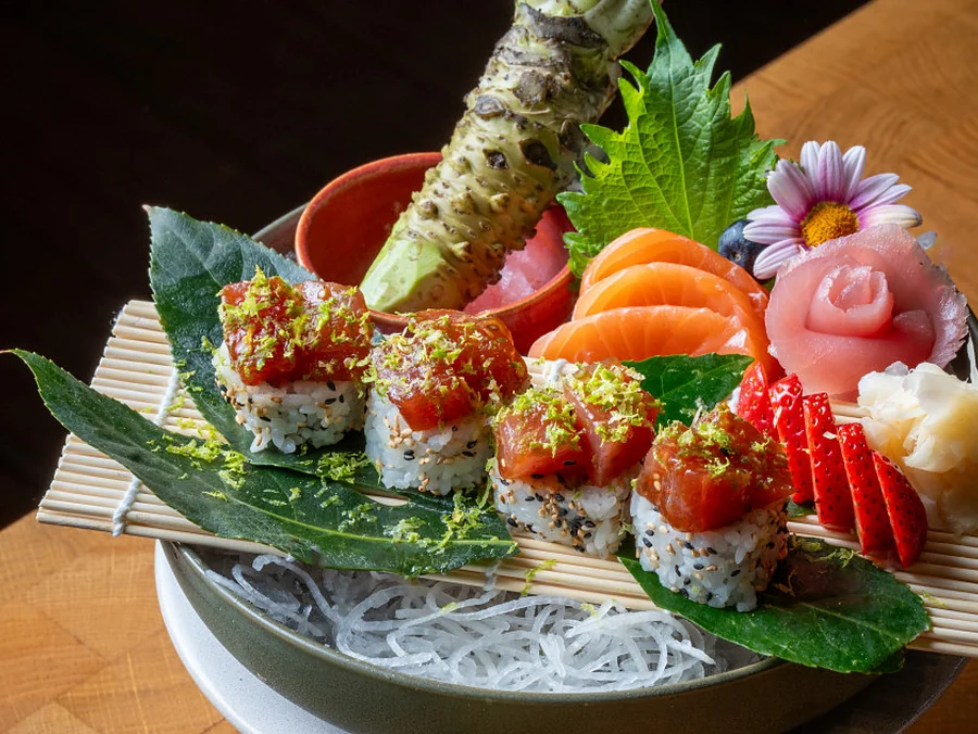 Sushi- und Sashimiplatte mit Lachs, Maki-Rollen, Wasabi und essbaren Blüten