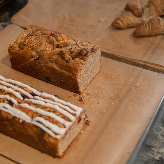 Zwei Kastenkuchen mit Nüssen und Zuckerguss auf Backpapier, daneben Croissants