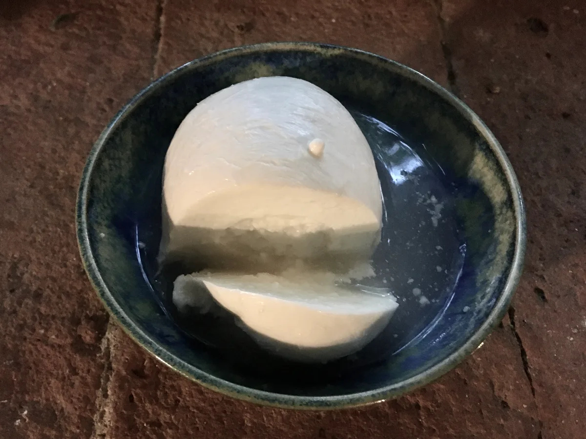 Aufgeschnittene Burrata in einer dunklen Schale