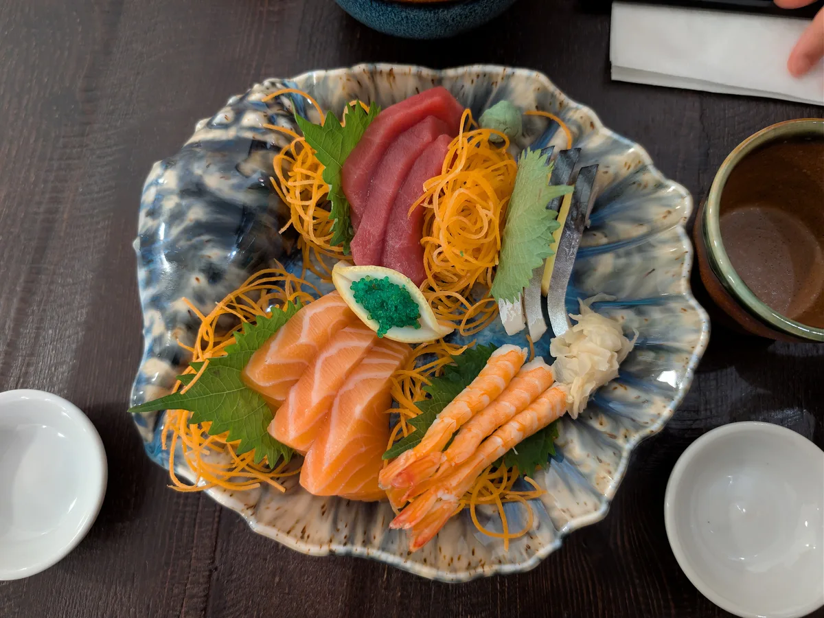 Sashimiplatte mit Thunfisch, Lachs, Garnelen und Ingwer auf einem gemusterten Teller