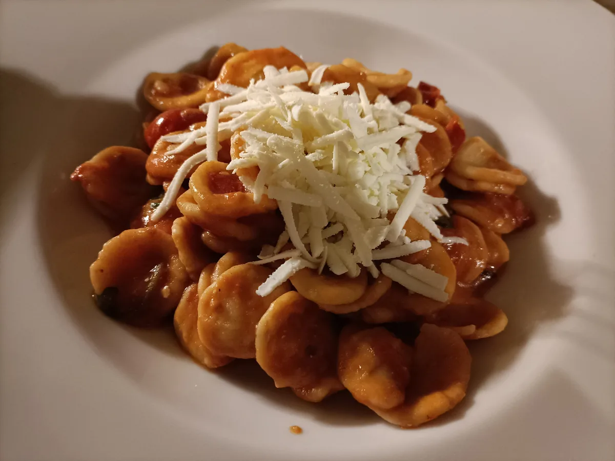 Orecchiette in Tomatensauce mit geriebenem Ricotta salata auf einem weißen Teller