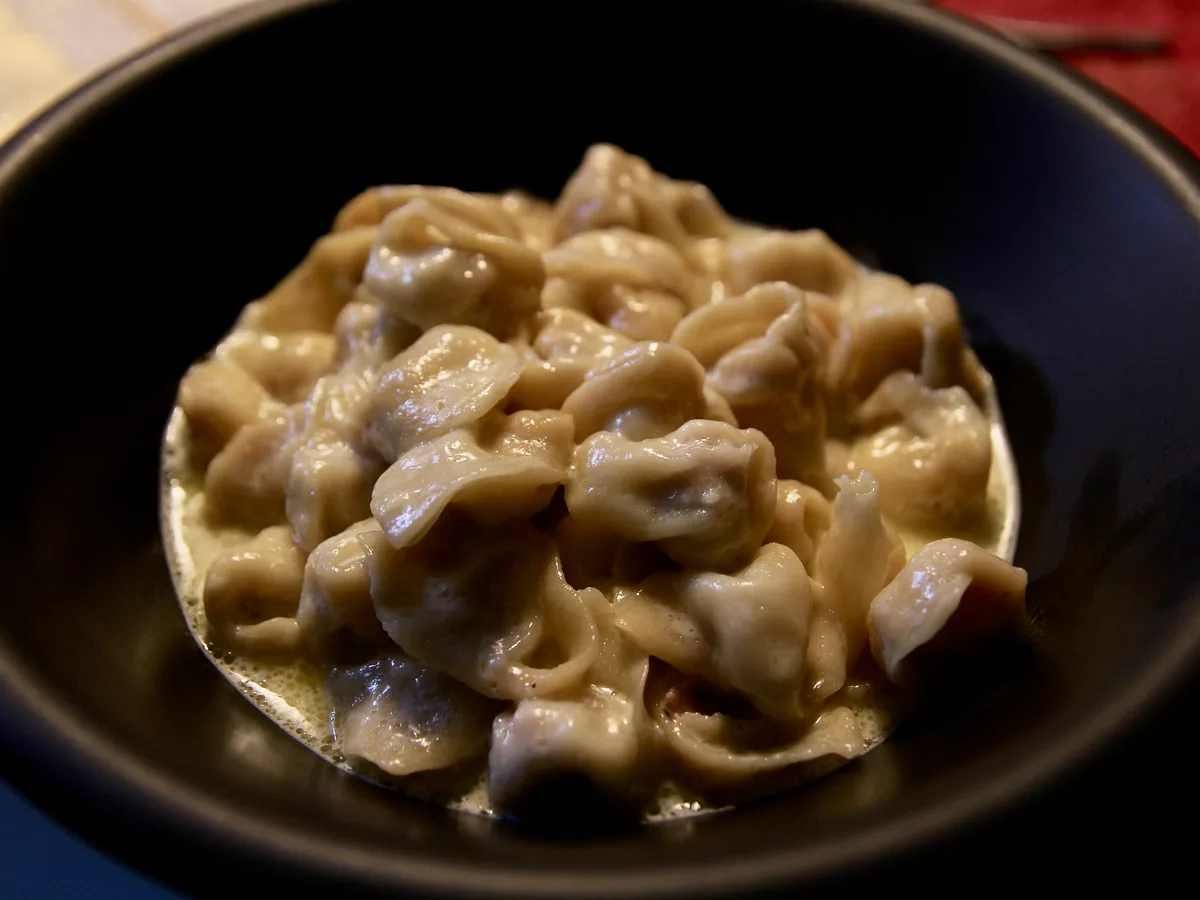 Tortellini in heller Sahnesauce in einer schwarzen Schale