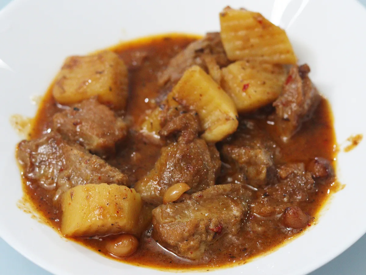 Massaman-Curry mit Fleisch, Kartoffeln und Erdnüssen auf einem weißen Teller