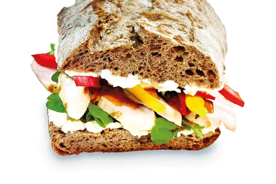 Aufgeschnittenes Sauerteig-Sandwich mit Frischkäse, Paprika, Tomate und Rucola