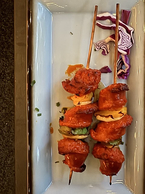 Zwei Spieße mit mariniertem Fleisch und Gemüse auf einer länglichen Platte