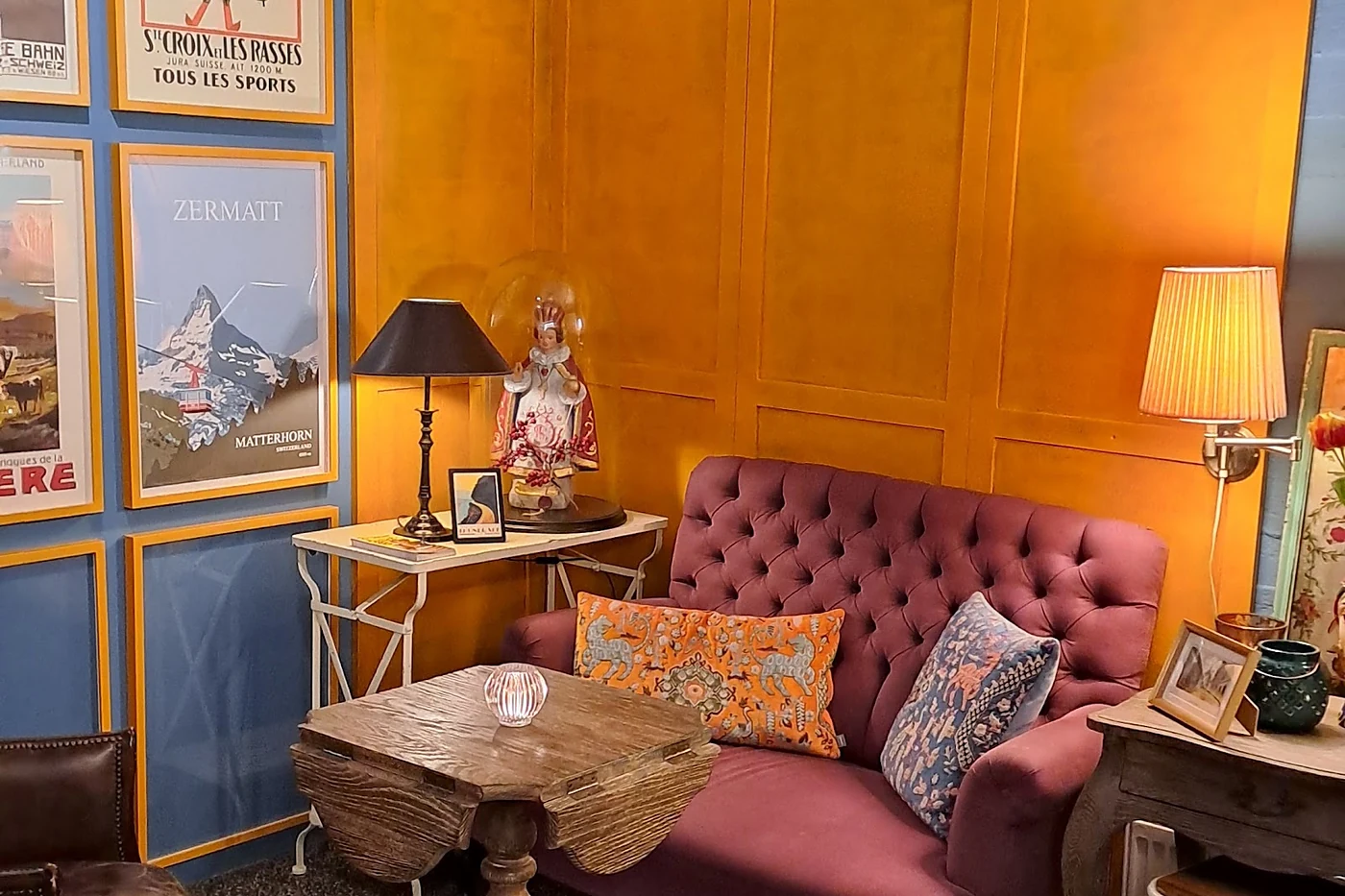 Sitzecke mit Sessel und Bildern vor blauer und orangefarbener Wand