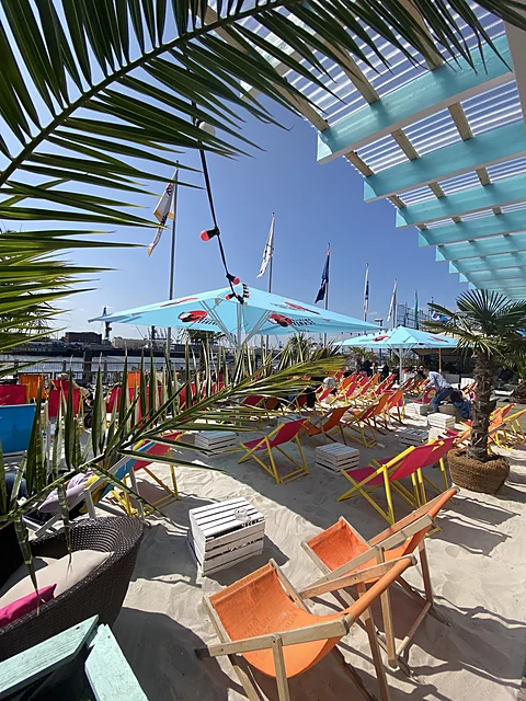 Bunte Liegestühle im Sand unter Palmen und Sonnenschirmen auf dem Parkdeck