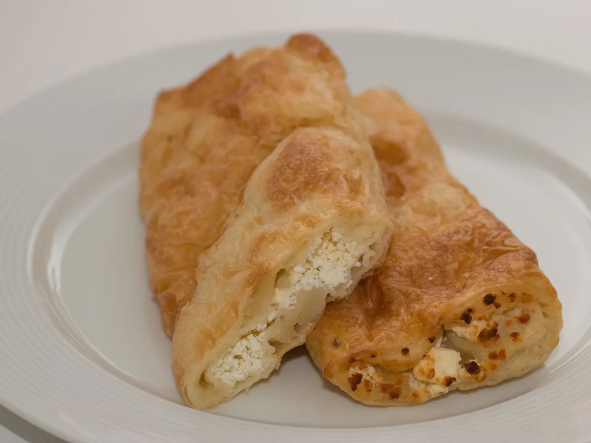 Zwei Stücke Börek mit Käsefüllung auf einem weißen Teller